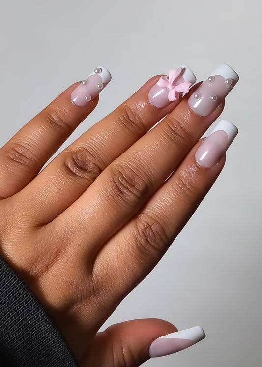 Hand with pink and white nail polish on a plain background
