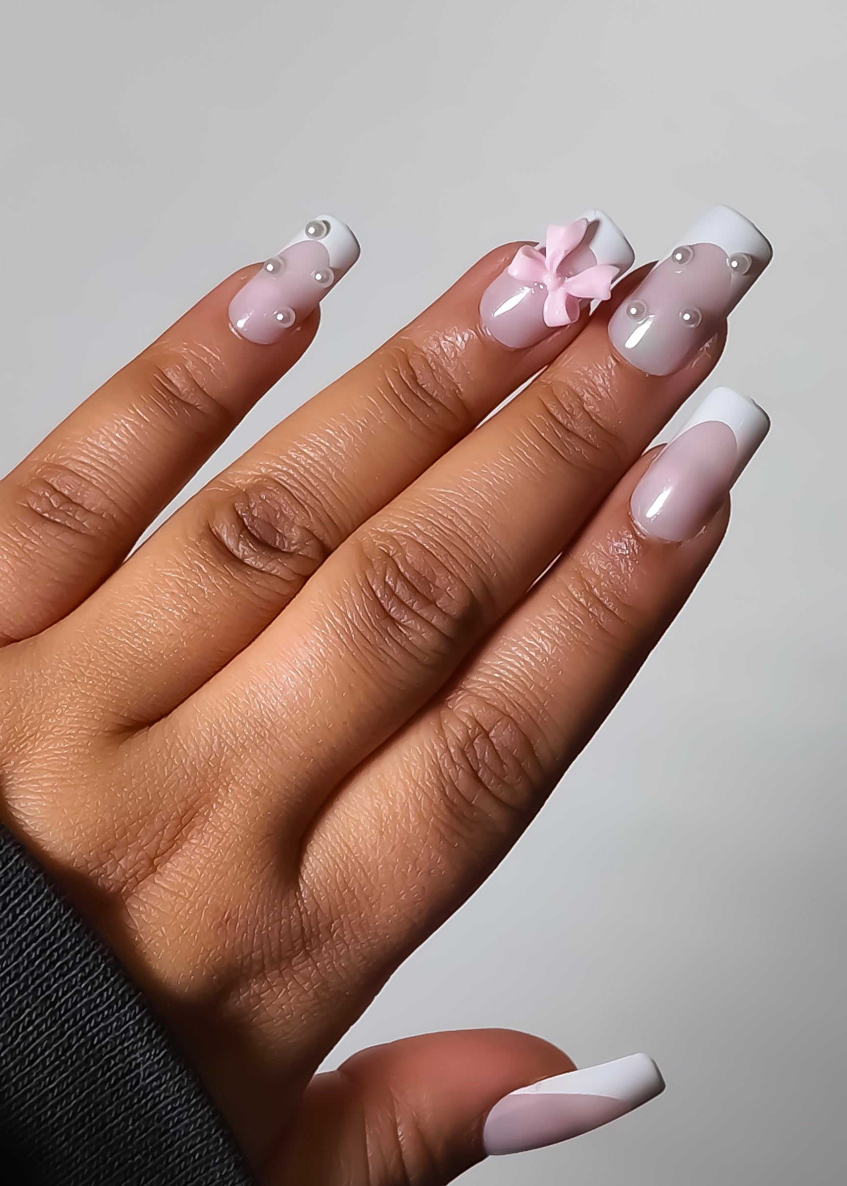 Hand with pink and white nail polish on a plain background